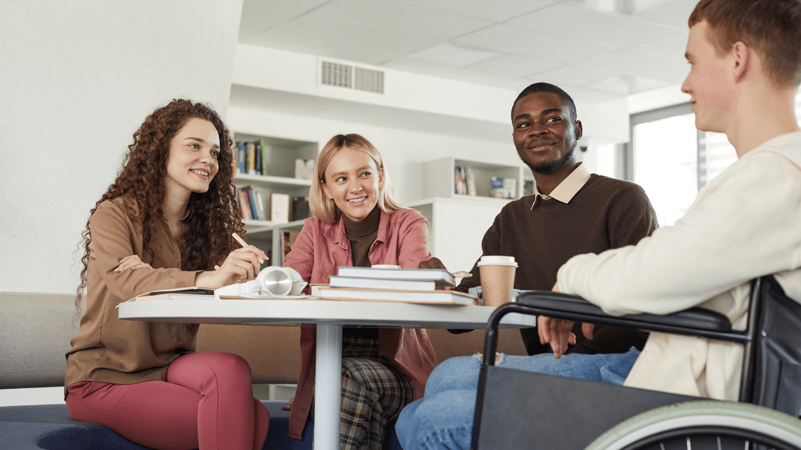 Students sitting at a table in a college, studying and working together.